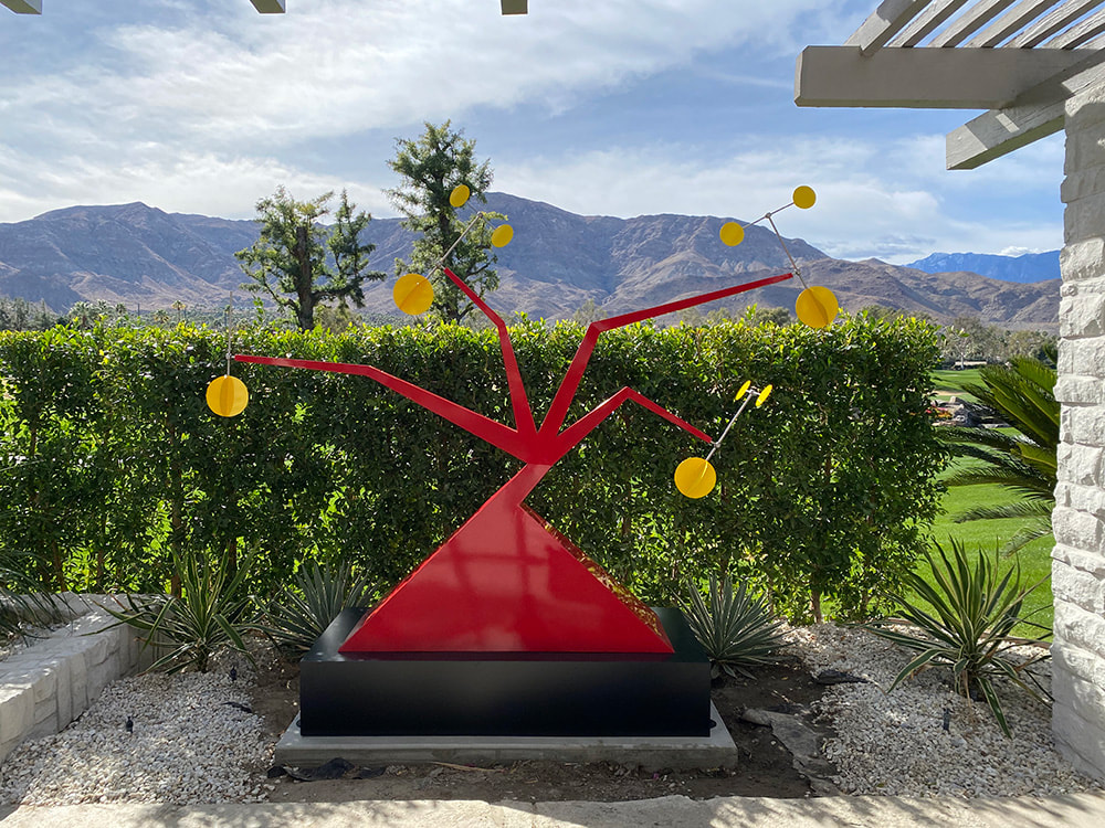 red abstract kinetic sculpture with mountains in the background