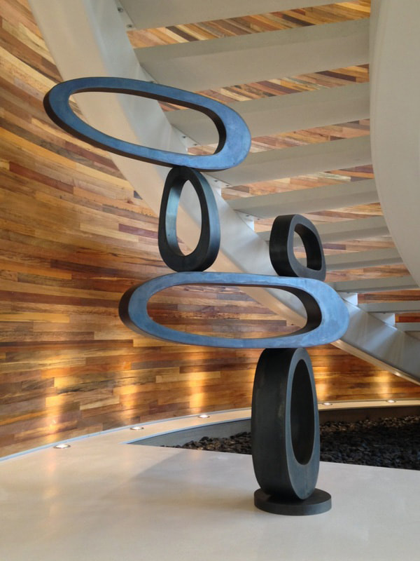 patinaed steel sculpture in apartment lobby oval shaped stacked upon itself