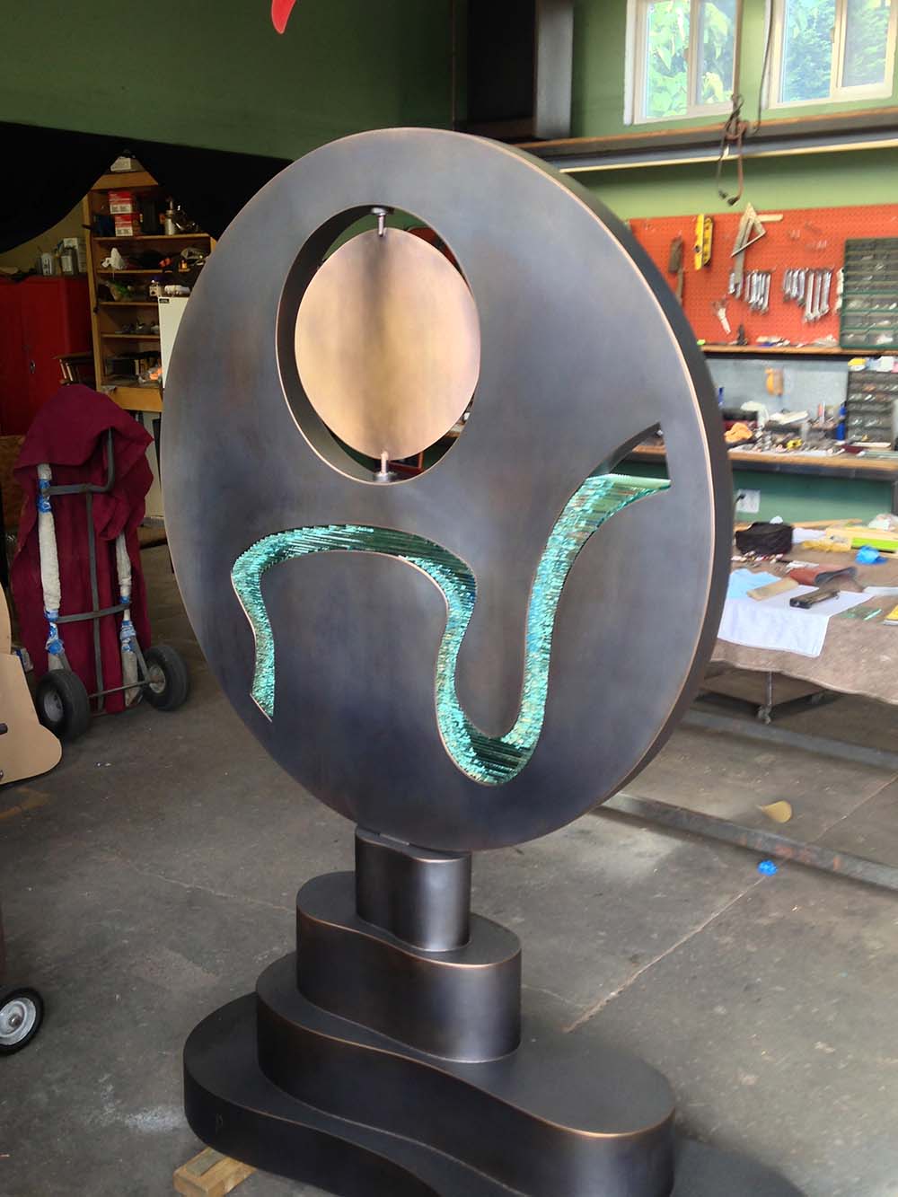 round bronze outdoor sculpture with circle kinetic element in studio