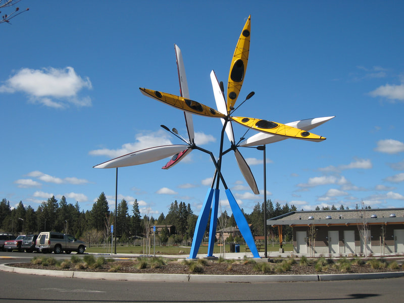 abstract sculpture in roundabout with 9 kayaks suspended I the air art in public places bend oregon