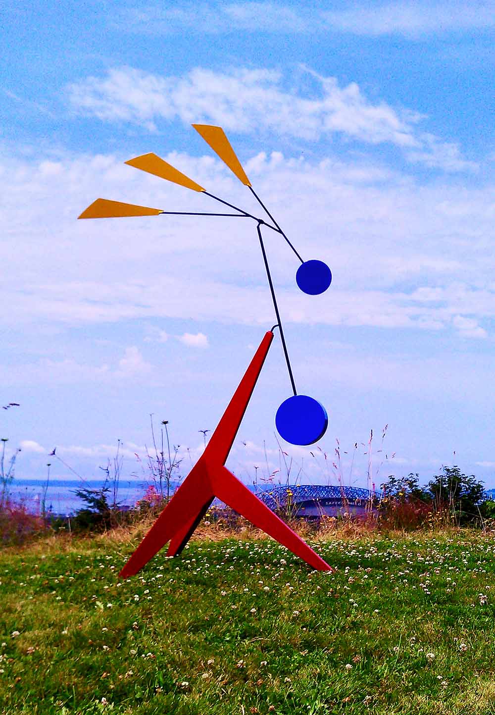 Modern red kinetic sculpture with blue moving circles and yellow fins