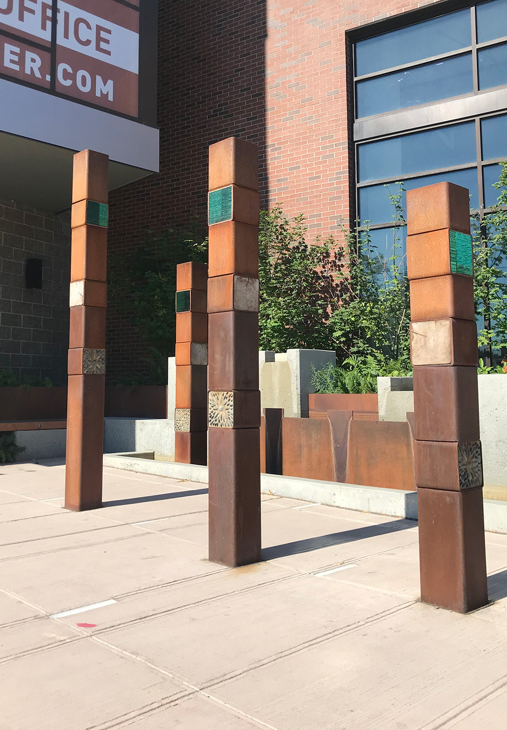plaza sculpture of four columns that have glass stone and wood