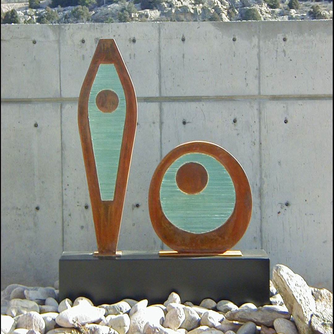 steel and glass sculpture with two shapes next to each other concrete backdrop
